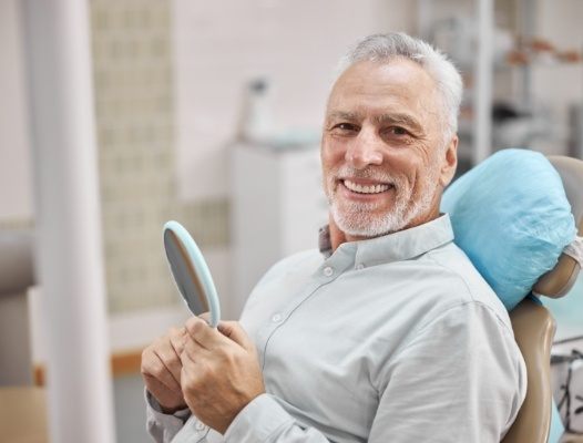 Man in dental chair smiling after all on four dental implant treatment