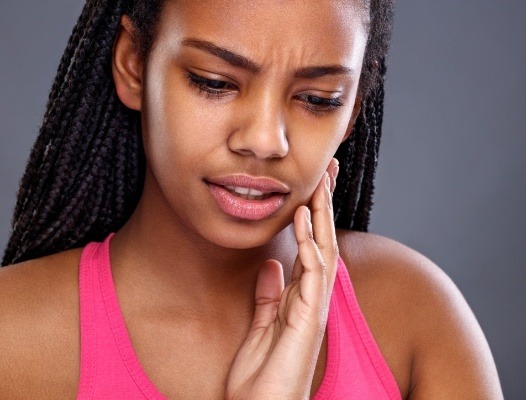 Woman with soft tissue injury holding jaw in pain