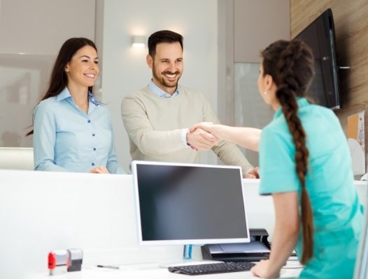 Two dental patients checking in at reception desk