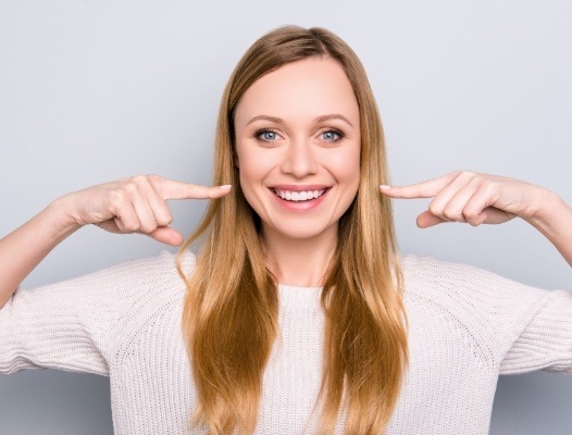 Woman pointing to smile after periodontal therapy