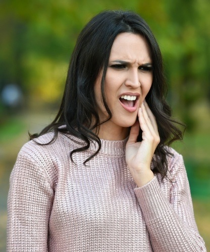 Woman in need of emergency dentistry holding jaw in pain